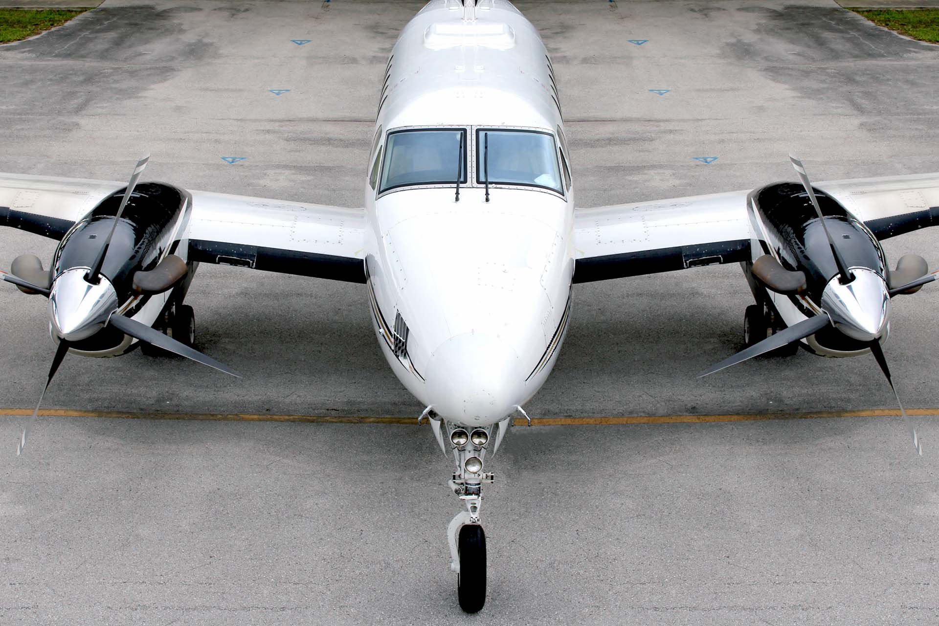 White business aircraft parked on the ramp with nosewheel in the front centered.